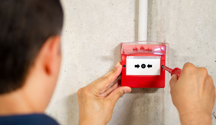 Technician installing fire alarm call point