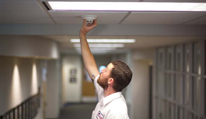 Technician installing smoke detector in hallway