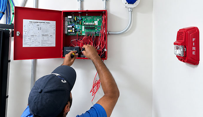 Technician servicing fire alarm control panel
